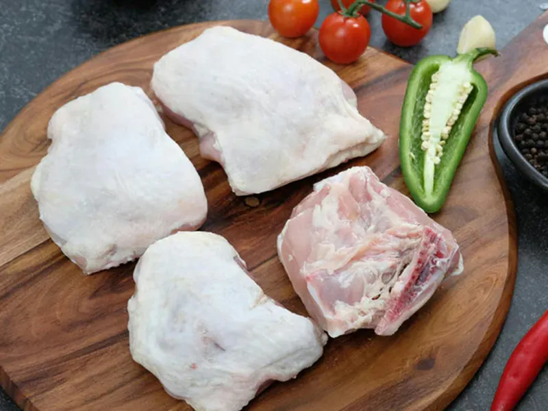 Raw chicken thighs on a wooden board
