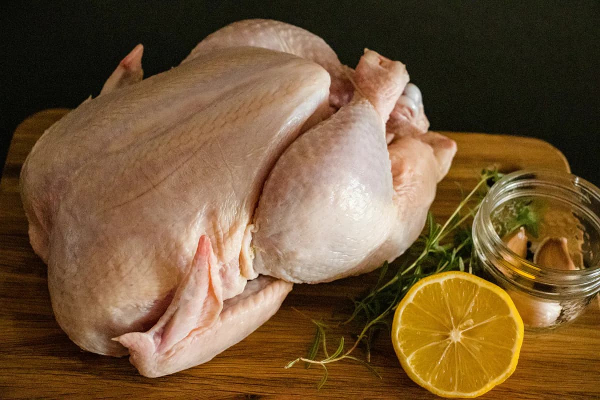 Whole raw chicken on a wooden board